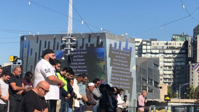 Ratusan umat Islam melaksanakan salat Jumat di Federation Square, alun-alun Kota Melbourne, Australia, pada 12 April 2019. Tampak nama-nama korban serangan teror di Christchurch ditampilkan melalui proyektor ke dinding gedung di sekitar lokasi.