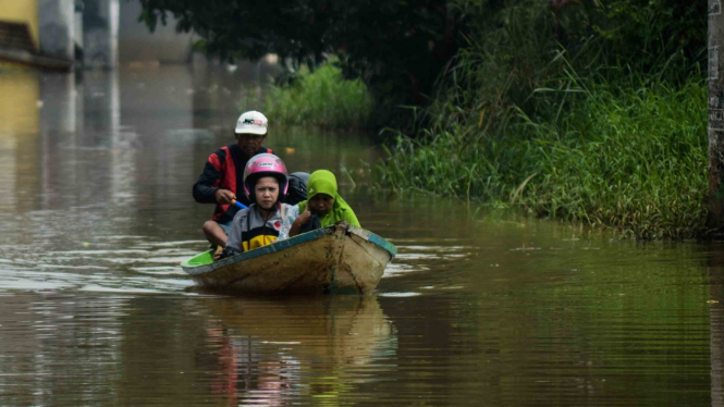 Warga menggunakan perahu untuk melintasi jalan yang tergenang banjir di Andir, Dayeuhkolot Kabupaten Bandung, Jawa Barat, Selasa, 16 April 2019.