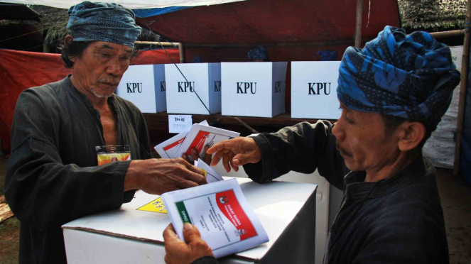 Warga Baduy Luar dibantu petugas TPS memasukan kertas suara usai melakukan pencoblosan dalam Pemilu 2019 di TPS 01 di Desa Kanekes, Lebak, Banten