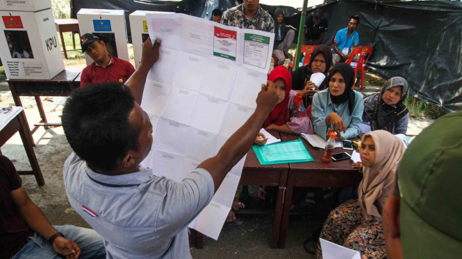 Anggota Kelompok Penyelenggara Pemungutan Suara (KPPS) menunjukkan surat suara kepada para saksi saat dilakukan perhitungan lanjutan di TPS bersebelahan dengan Pos Lanal Pusong di Desa Pusong Baru, Lhokseumawe, Aceh