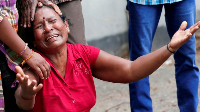 Seorang anggota keluarga tak kuasa menahan tangis ketika menunggu di luar ruang jenazah di kantor polisi di Kolombo, Minggu (21/04). - Reuters