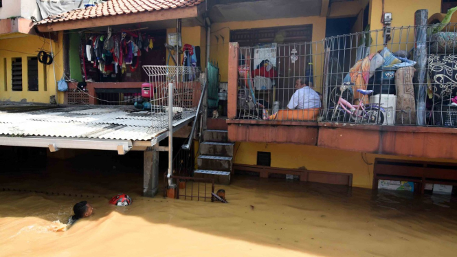 Warga bertahan di rumahnya saat banjir melanda kawasan Rawajati, Jakarta Selatan, Jumat, 26 April 2019.