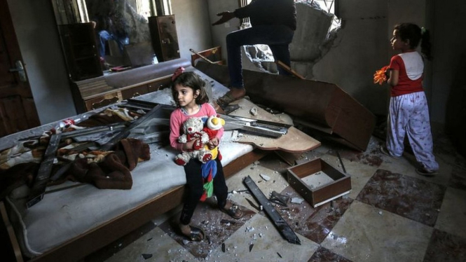 Dua bocah perempuan, yang memegang bonekanya, bersama ayahnya di ruangan tidur di rumahnya di Rafah, Gaza, tidak lama setelah Israel melakukan serangan roket ke kawasan itu, Minggu (05/05). - SAID KHATIB/AFP