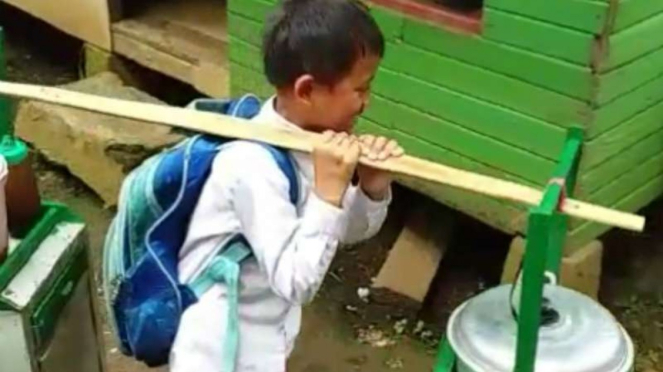 Erwin, seorang bocah pelajar sekolah dasar, memanggul gerobak baksonya dari ruma