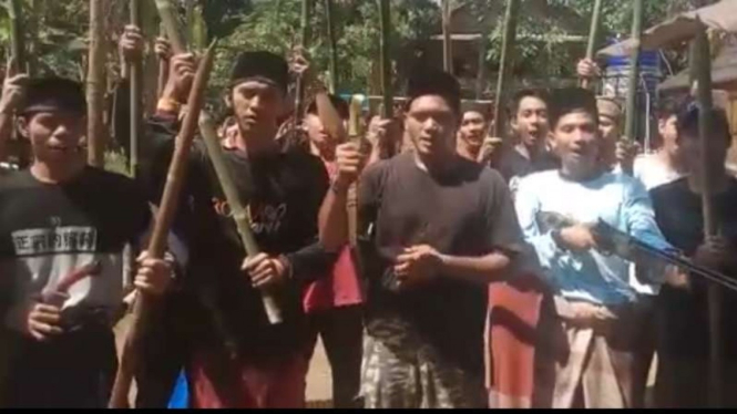 Sebuah video yang memperlihatkan sekelompok orang membawa golok, bambu runcing, sampai senjata laras panjang, viral di media sosial.