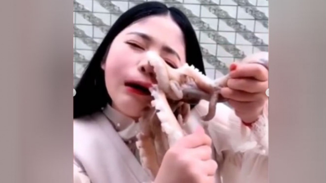 Wanita makan gurita hidup-hidup.