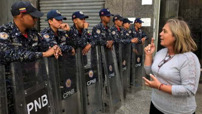 Seorang perempuan berbicara di hadapan para anggota kepolisian yang berjaga di dekat gedung parlemen Venezuela.-AFP/Getty Images