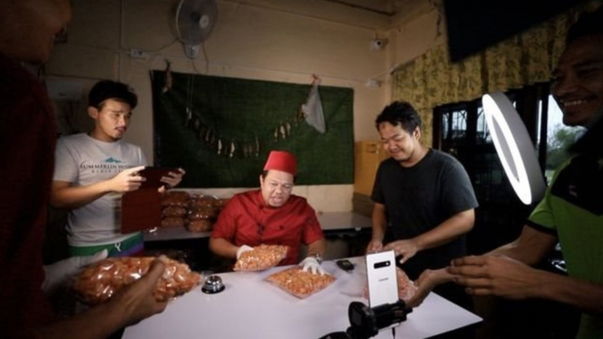 Hasan sedang melakukan Facebook live dibantu oleh para stafnya - PARIS JITPENTOM/BBC THAI
