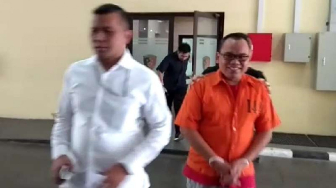 Mustofa Nahrawardaya berbaju tahanan dan diborgol.