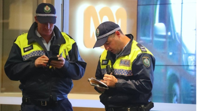 Dua polisi berdiri di depan pintu masuk kantor redaksi ABC di Sydney, Australia. - EPA