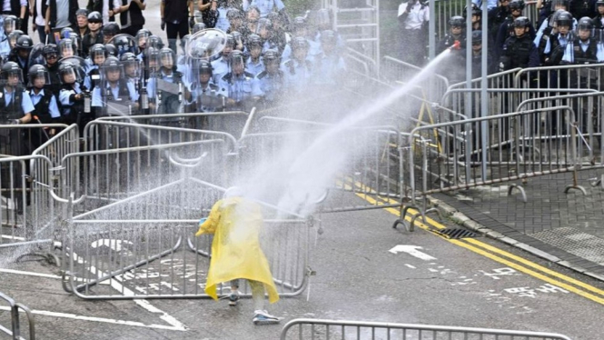 Polisi menggunakan meriam air untuk menghalau seorang demonstran dekat gedung pemerintah, Rabu (12/06). - Getty Images