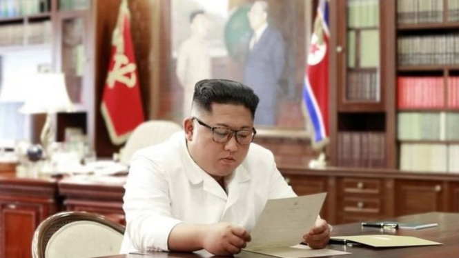 Kim Jong-un sedang membaca surat dari Presiden AS Donal Trump.-AFP