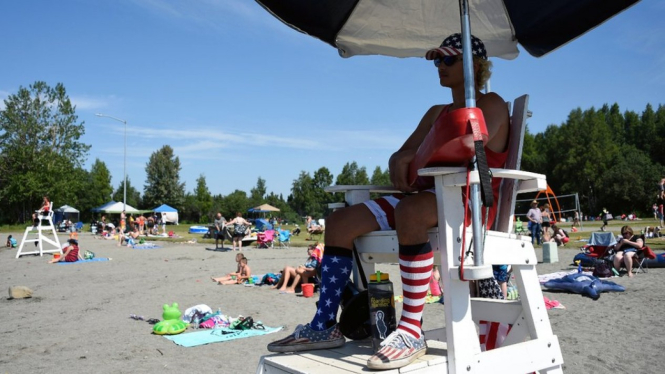 A lifeguard watches as people sunbathe at Jewel Lake, Anchorage - Getty Images