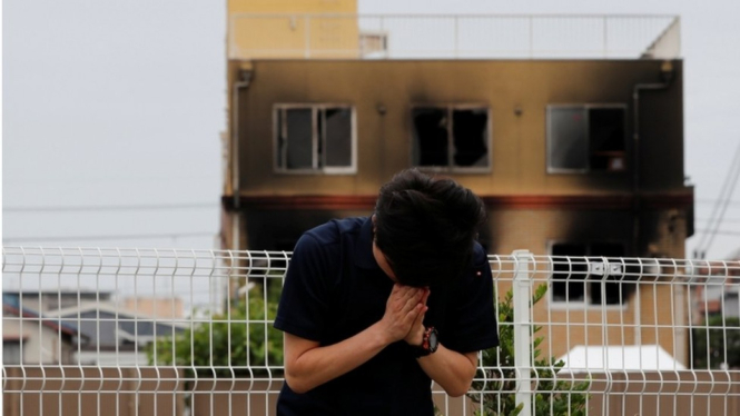 Seorang warga berdoa di depan gedung studio Kyoto Animation yang diduga dibakar. - Reuters