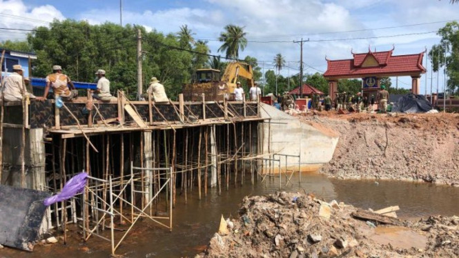 Para pekerja sedang membangun jembatan ke pangkalan Angkatan Laut di Kamboja.