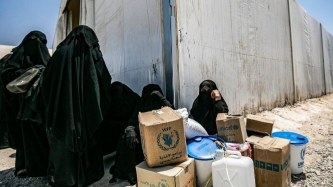 Perempuan di kamp Al-Hol, duduk di dekat kotak-kotak bantuan. - AFP