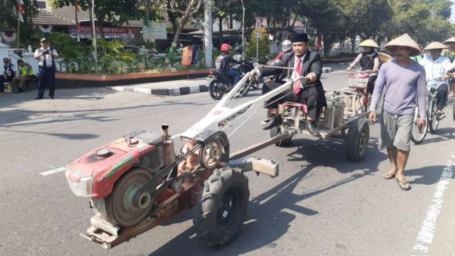 Wawan Prasetia, anggota DPRD Sleman, naik traktor untuk menghadiri pelantikannya sebagai wakil rakyat di kantor Bupati Sleman, Daerah Istimewa Yogyakarta, Senin, 13 Agustus 2019.