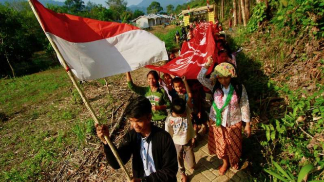 Warga Dayak Meratus berjalan menuju desa dengan membawa bendera Merah Putih dalam rangka memeriahkan HUT ke-74 Kemerdekaan RI di Desa Kiyu, Kabupaten Hulu Sungai Tengah, Kalimantan Selatan, Sabtu (17/8/2019). 