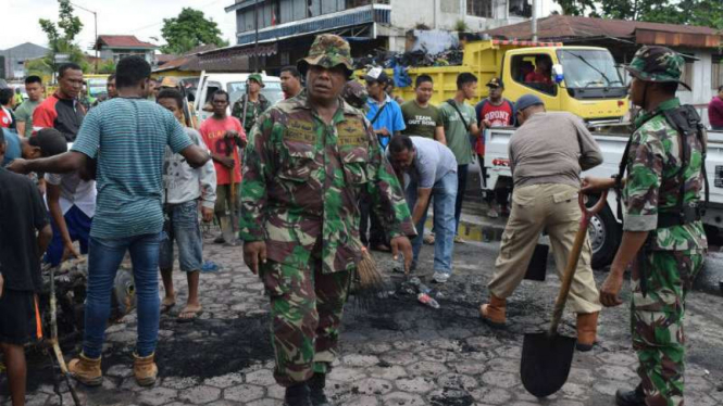 Warga Manokwari bersama TNI membersihkan sisa-sisa pembakaran di jalan.