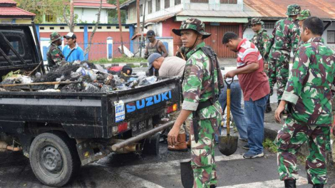 Warga Manokwari bersama TNI membersihkan sisa-sisa pembakaran di jalan.
