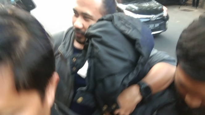 Aulia Kesuma (wajah ditutupi jaket), tersangka kasus pembunuhan yang korbannya dibakar di dalam mobil, dibawa ke Markas Polda Metro Jaya, Kamis, 29 Agustus.