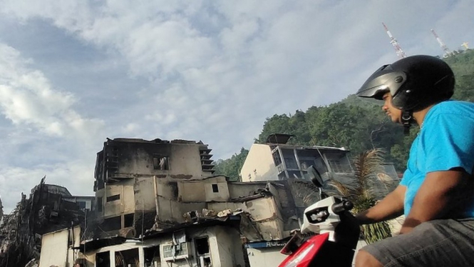 Seorang warga melintasi puing bangunan yang terbakar seusai aksi unjuk rasa di Jayapura, Papua, Jumat (30/8/2019). Sejumlah bangunan dan kendaraan terbakar saat aksi pada (29/08) - Indrayadi TH/ANTARA FOTO