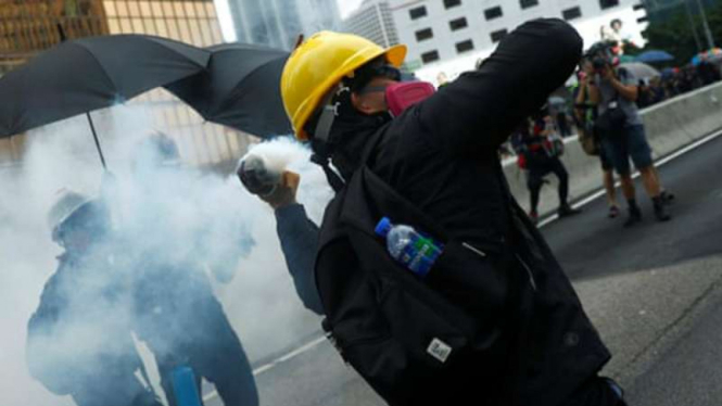 Seorang demonstran melempar tabung gas air mata ke arah polisi saat demonstrasi di Hong Kong pada hari Sabtu