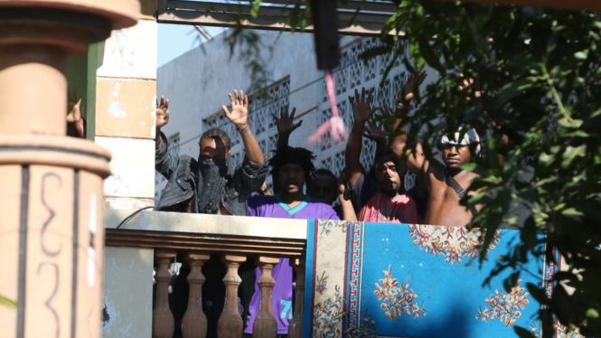 Penghuni Asrama Kamasan mengangkat tangan tanda saat aparat kepolisian menangkap mereka. - Antara Foto/Didik Suhartono