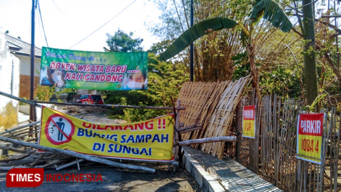 Sejumlah banner dipasang warga di lokasi jalan longsor yang berada di kawasan sungai Gandong Magetan. (FOTO: M Kilat Adinugroho/TIMES Indonesia)