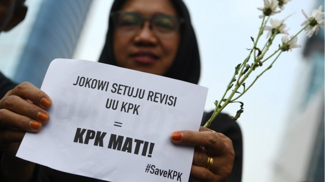 Pegawai KPK membawa bunga dan poster untuk dibagikan kepada warga pada melakukan aksi saat Hari Bebas Kendaraan Bermotor di kawasan Bundaran HI Jakarta, Minggu (8/9). - Antara/WAHYU PUTRO A