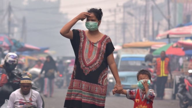 Seorang ibu dan anaknya mengenakan masker medis saat asap kebakaran hutan dan lahan (Karhutla) menyelimuti Kota Pekanbaru, Riau, Selasa (10/09). - ANTARA FOTO/FB Anggoro