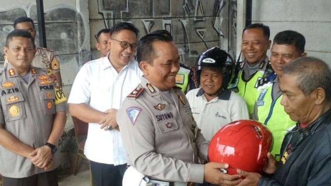 Satlantas Depok membagikan helm kepada pengendara yang tertib berlalu lintas.