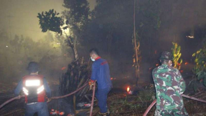 Petugas memadamkan kebakaran hutan dan lahan di Riau.