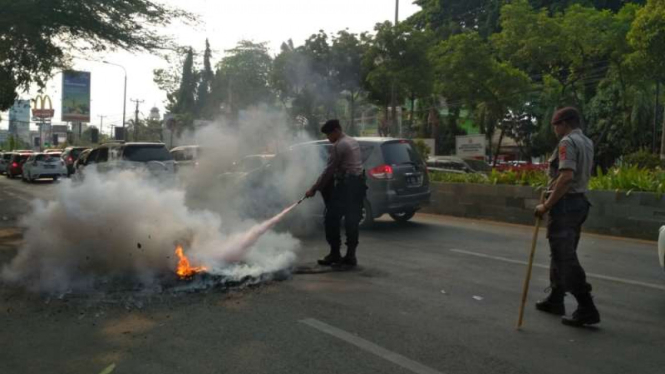 Polisi memadamkan ban bekas yang dibakar oleh massa mahasiswa dalam aksi demonstrasi di Kota Serang, Banten, Rabu, 25 September 2019.