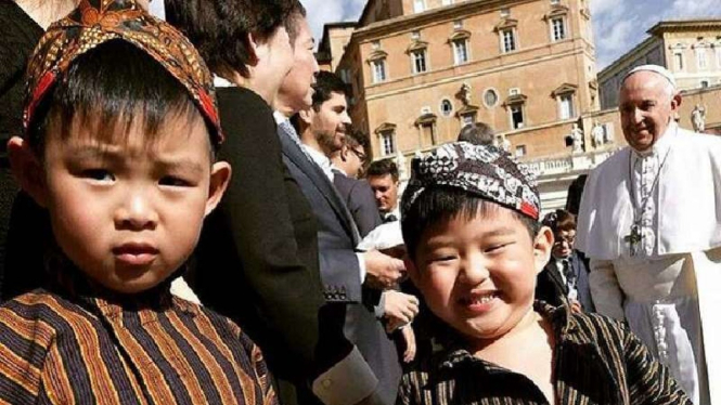 Dua anak laki-laki berpakaian Jawa dengan Paus Fransiskus.