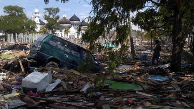 Puing bangunan, gelondongan kayu, hingga mobil berserakan di sekitar Masjid Agung Baiturrahman setelah tsunami melanda Aceh tahun 2004 lalu - BAY ISMOYO/AFP/Getty Images