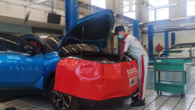Teknisi sedang servis mobil Toyota C-HR Hybrid di bengkel Auto2000 Banyuwangi.