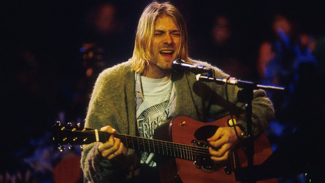 Kurt Cobain, yang bunuh diri pada April 1994 di usia 27 tahun itu, mengenakan sweater hijau selama tampil dalam acara MTV Unplugged pada 1993. - Frank Micelotta Archive/Geety