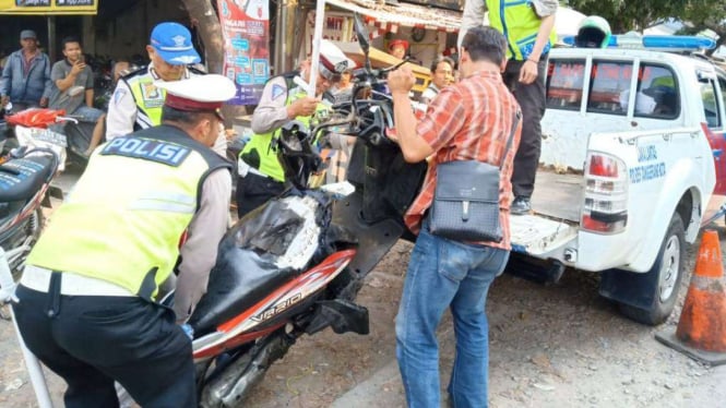 Petugas polisi mengevakuasi motor korban yang tertabrak kereta bandara.