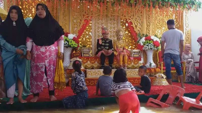 Sebuah resepsi pernikahan warga Aceh Barat, Aceh, digelar di tengah banjir yang tak kunjung surut.