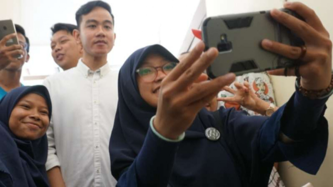 Putra sulung Jokowi, Gibran Rakabuming Raka berfoto dengan warga.