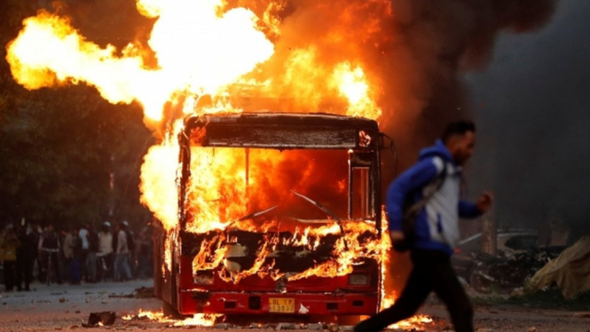 Sebuah bus dan beberapa sepeda motor dibakar dalam demonstrasi menentang UU Kewarganegaraan di Delhi, India, Minggu (15/12). - Reuters