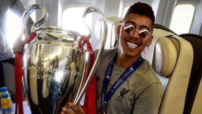 Penyerang Liverpool, Roberto Firmino, menggenggam trofi Liga Champions