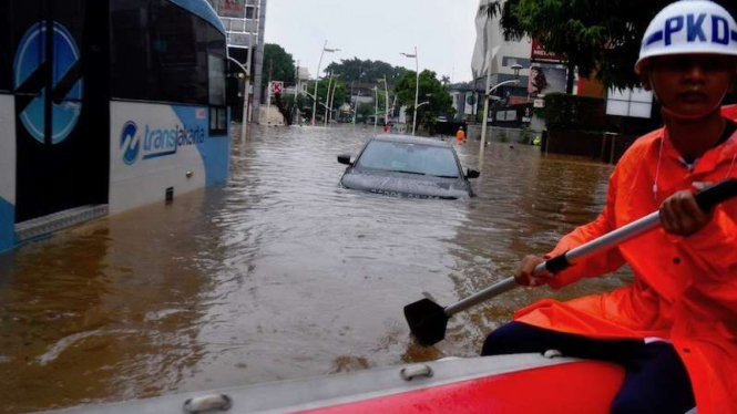 Petugas keamanan mendayung perahu karet saat banjir Jakarta