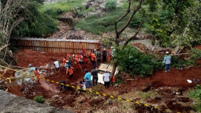 Petugas melakukan evakuasi terhadap makam yang tertimbun longsor di Depok.