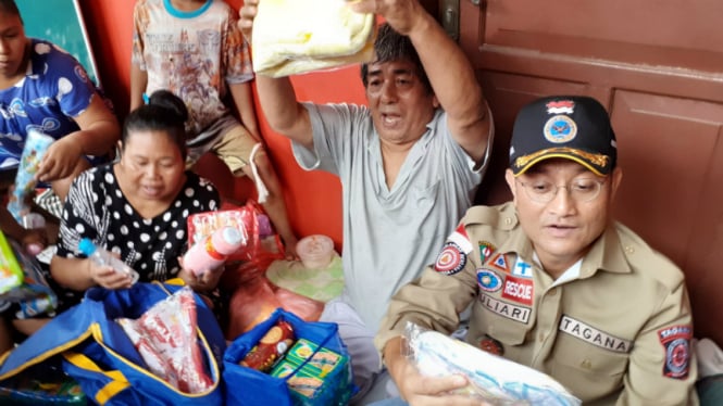 Menteri Sosial, Juliari Barubara, membagikan logistik kepada korban banjir