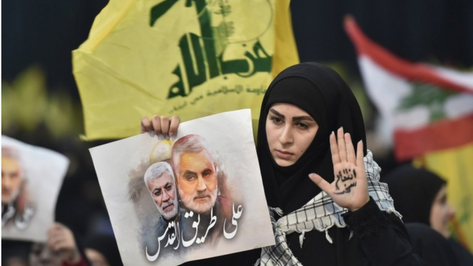 Seorang perempuan pendukung Hezbollah membawa foto Jenderal Qasem Soleimani, komandan pasukan elite Quds dari Garda Revolusi Iran yang tewas dibunuh pasukan Amerika Serikat. Aksara Arab pada telapak tangan perempuan itu bertuliskan Menuju ke Quds". - EPA"