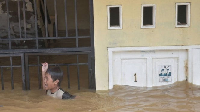Di depan rumah di kawasan Kampung Melayu, Jakarta Timur, yang terendam banjir, seorang bocah terlihat bermain. - Agung Fatma Putra/Getty