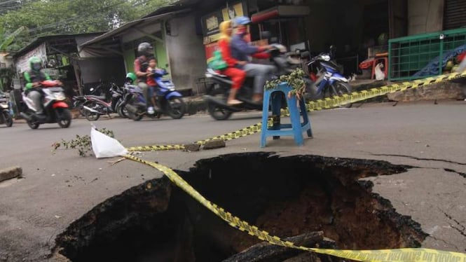 Sejumlah pengendara melintas di jalan yang amblas di kawasan Cibubur, Jakarta Timur, Kamis (2/1/2020). Kondisi jalan tersebut mengalami kerusakan di satu sisi jalan yang dapat membahayakan pengendara yang melintas terutama pada malam hari. 