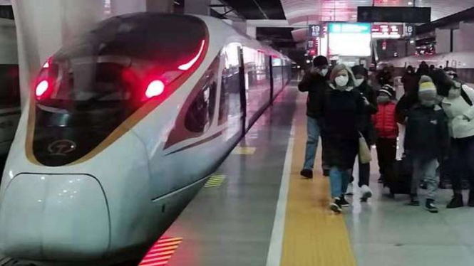 Para penumpang kereta cepat baru tiba di Stasiun Tianjin, Kamis (22/1) malam, dengan mengenakan masker untuk menghindari wabah virus corona jenis baru di Wuhan, China. 